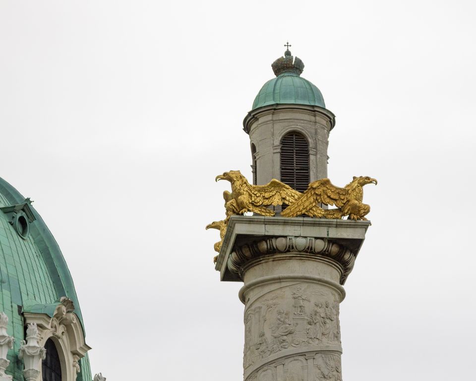 Golden eagles atop a carved column beside a green dome