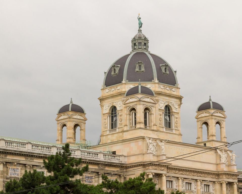 Museum with a dark domed cupola and twin turrets under grey sky