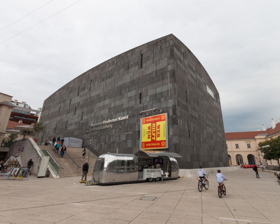 Dark stone modern art museum with a trailer café and cyclists