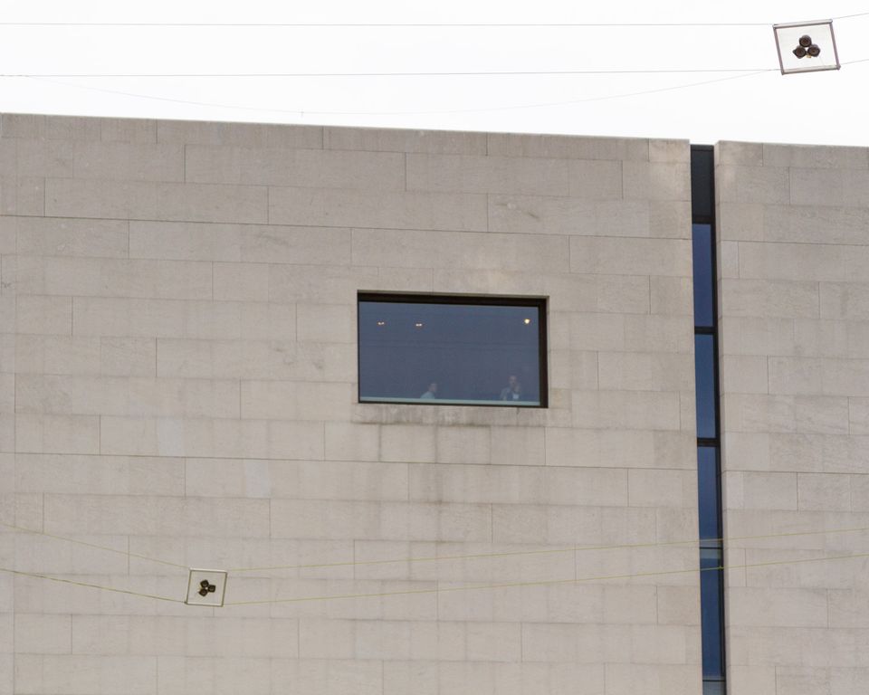 Plain stone wall with a single window and cables with small signs