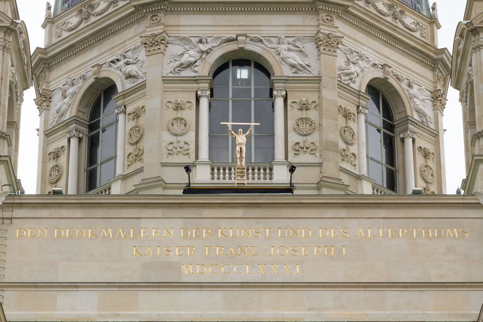 Gilded statue and gold lettering above the windows of a domed museum