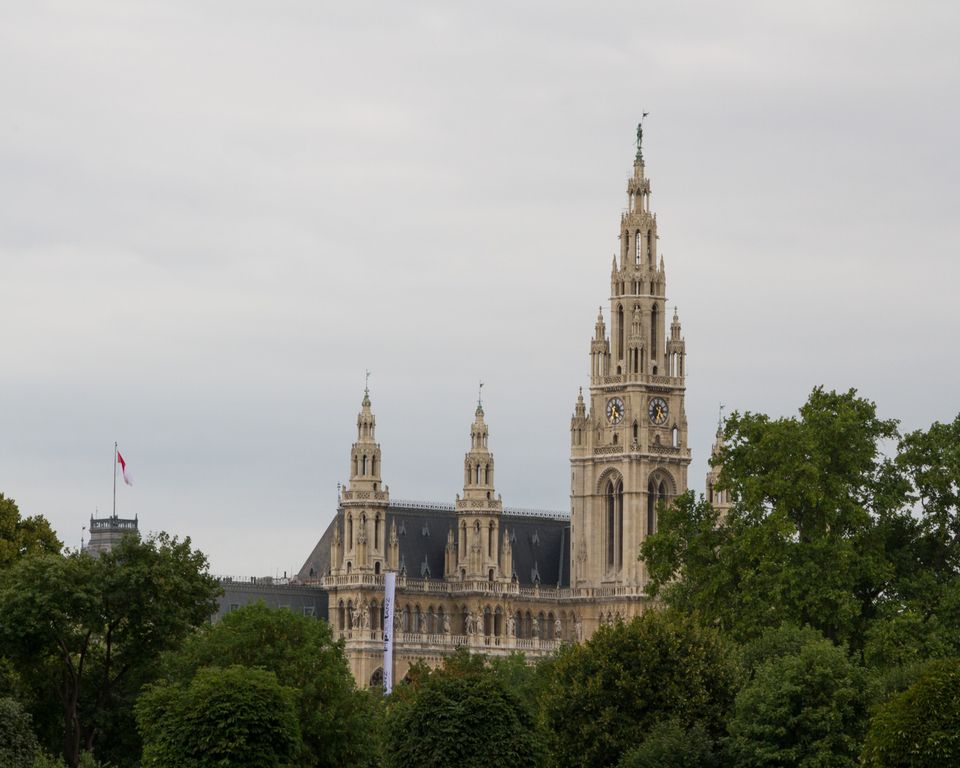 Neo-Gothic hall with a tall spired tower above green trees