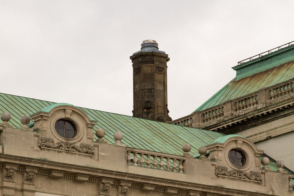 Green copper roof with a weathered stone chimney and round windows