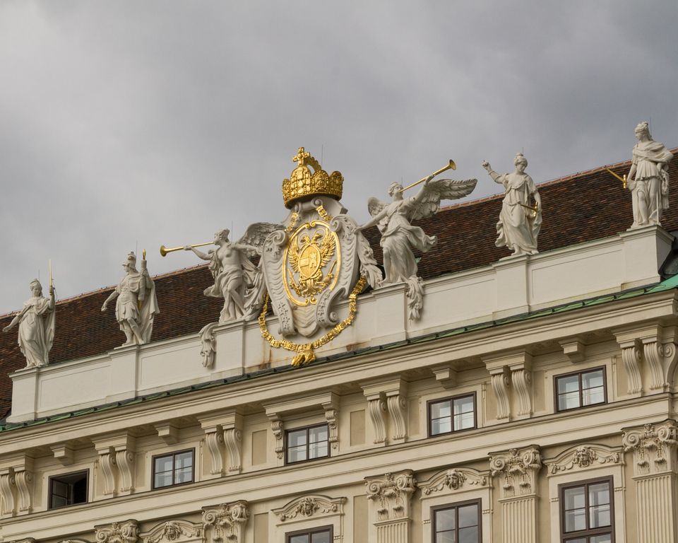 Golden crown and coat of arms flanked by trumpeting white angels