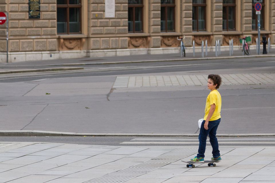Boy in a yellow shirt on a skateboard on empty pavement