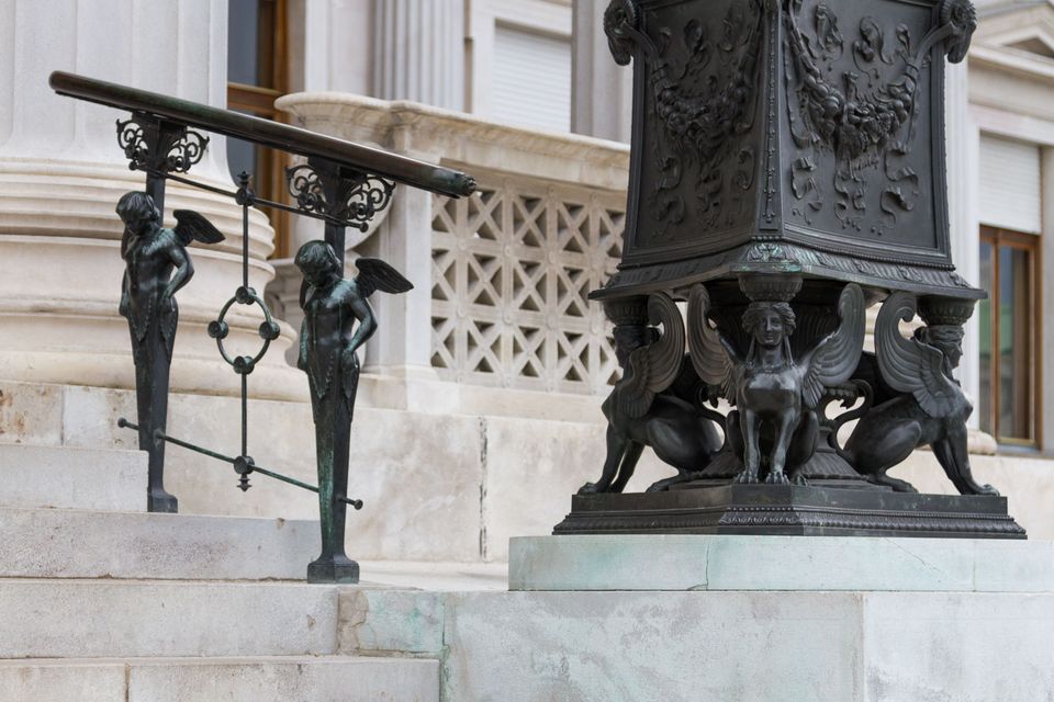 Dark bronze winged figures on a stair railing and lamp base
