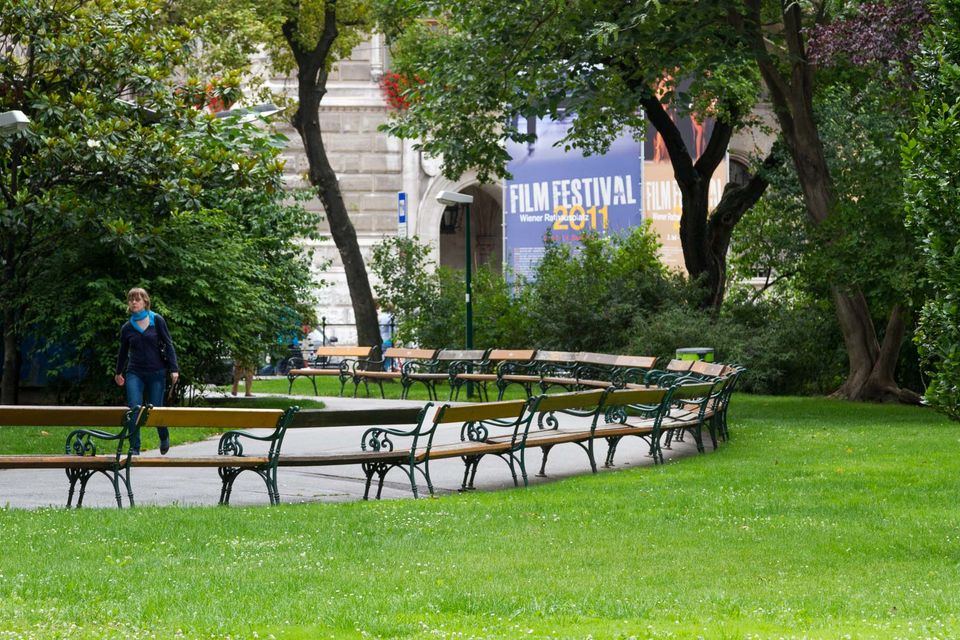 Curved park benches on a lawn beneath trees