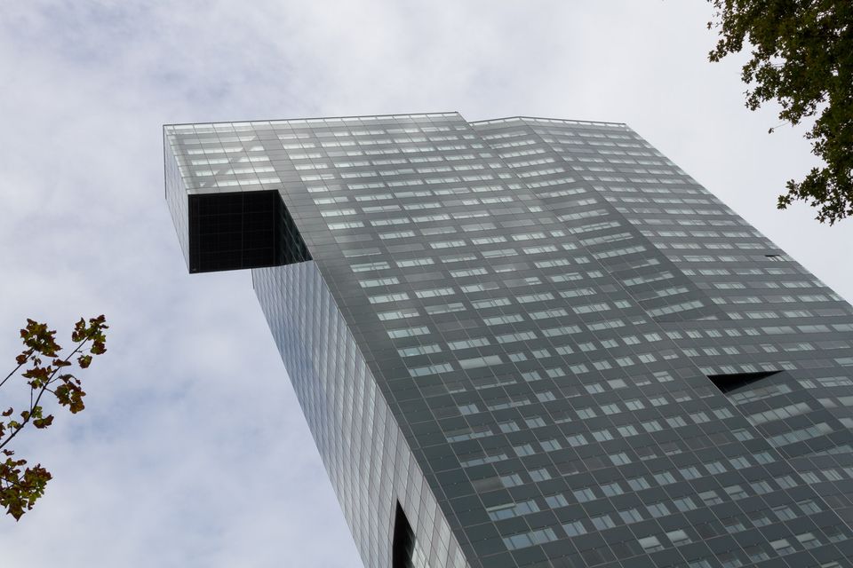 Glass skyscraper with a cantilevered top seen from below