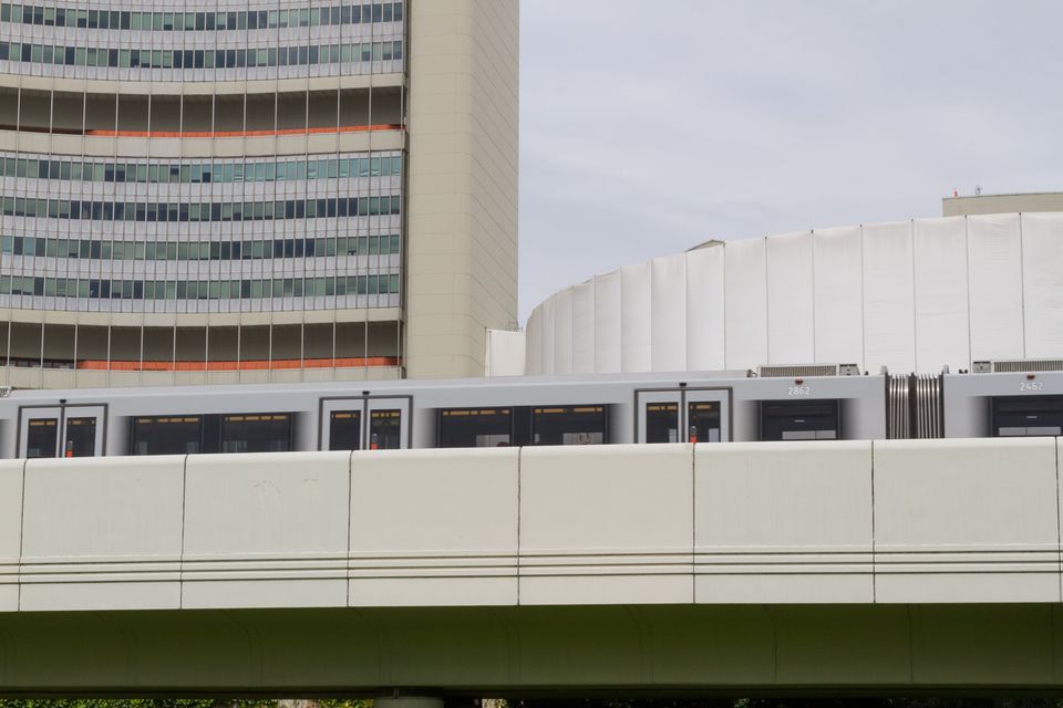 Metro train on a viaduct before a curved tower and round building