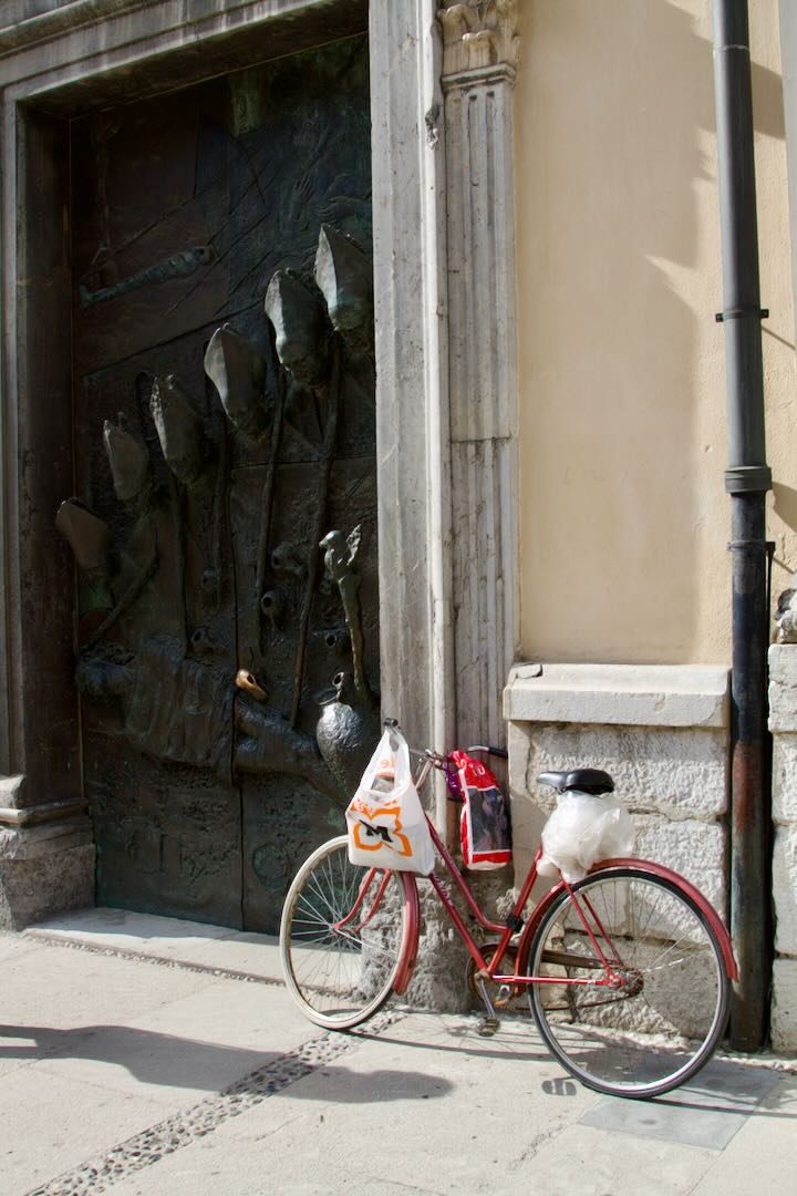 Red bicycle leaning against a carved wooden door