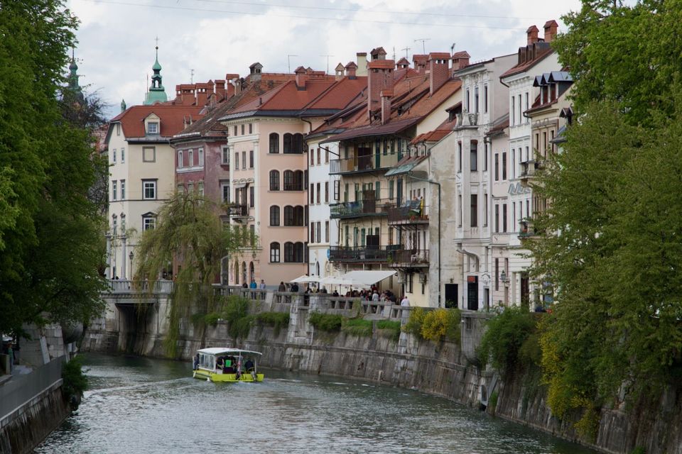 Tourist boat on the Ljubljanica below pastel riverside houses
