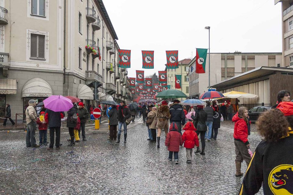 Crowd under umbrellas in a rainy street hung with banners