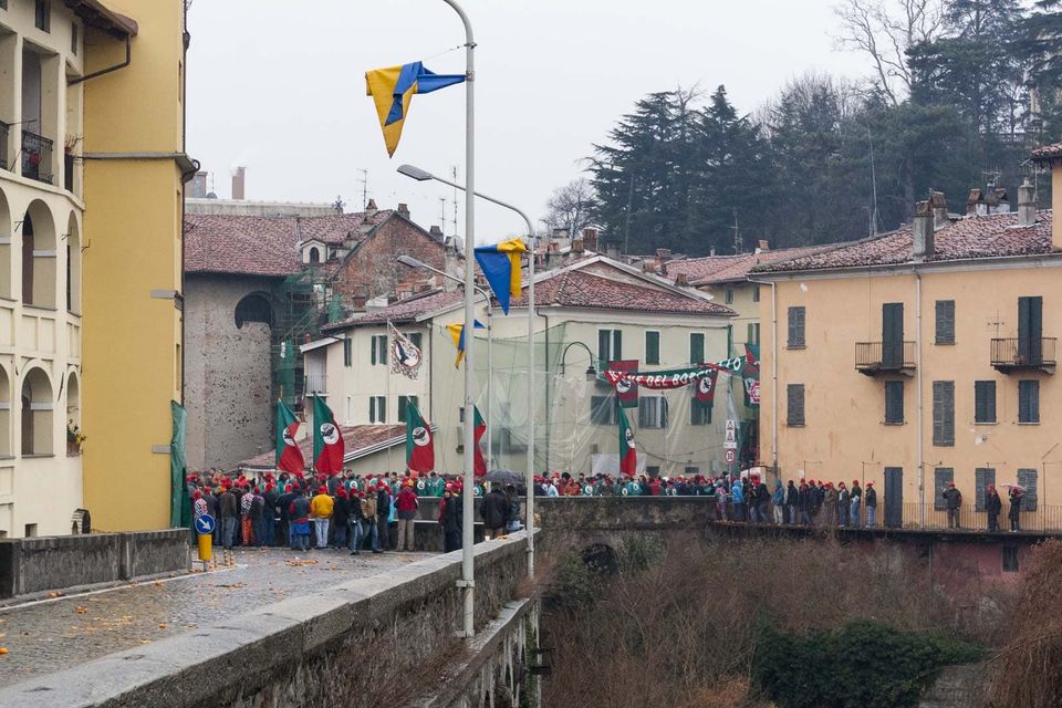 Crowd at a bridge beneath flags with the nets-covered street beyond