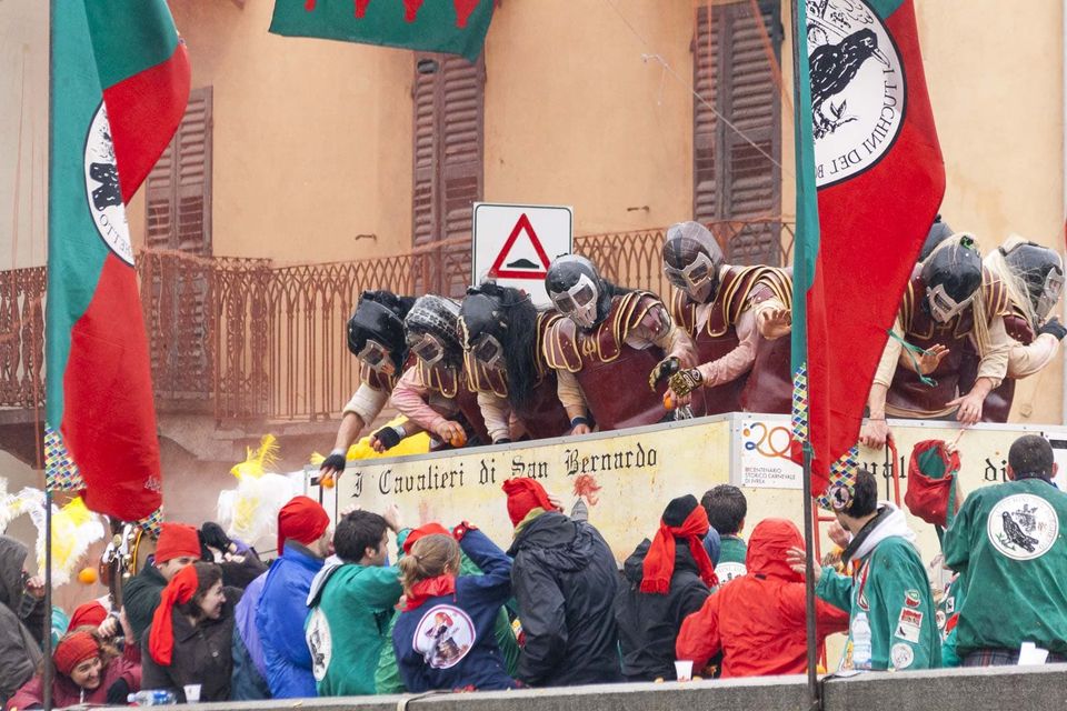 Armoured throwers on a cart hurling oranges at the crowd below