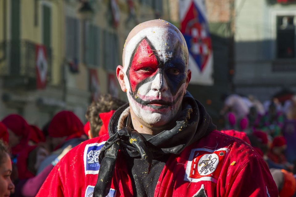 Man in white face paint with red and black diamonds