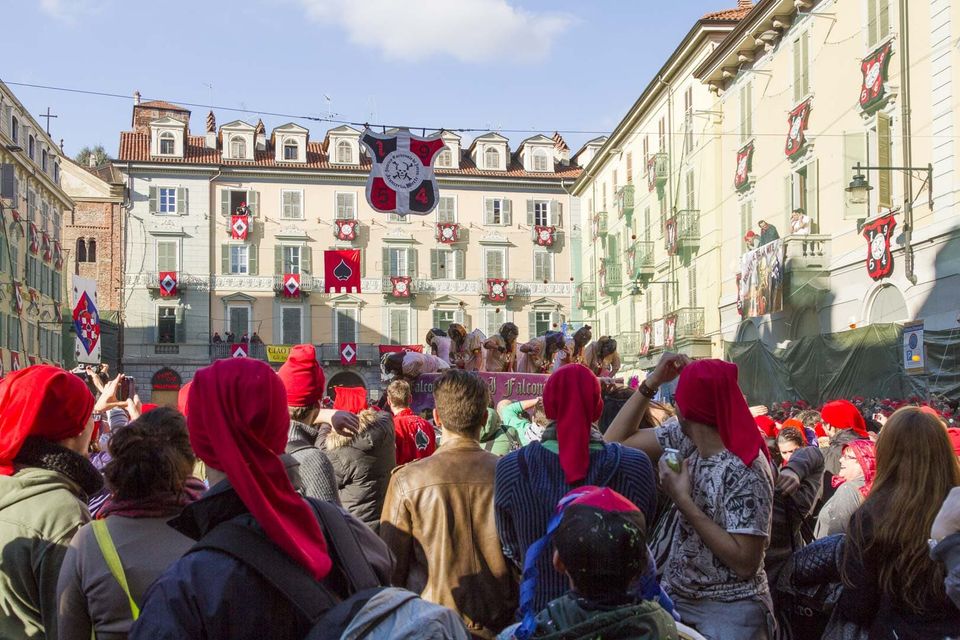 Crowd of red caps in front of a palazzo with red banners