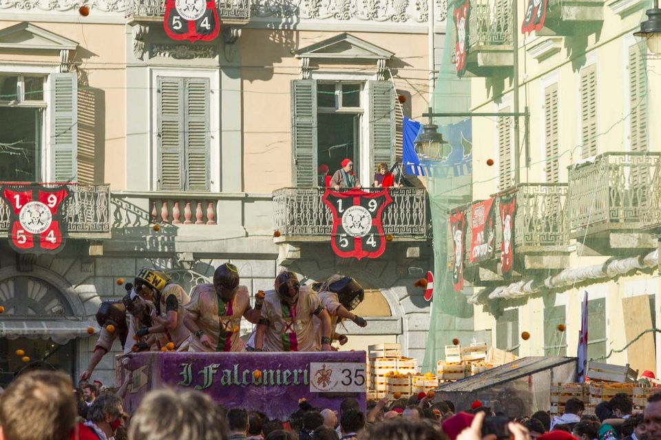 Armoured throwers on a cart throw oranges past balconies with team crests