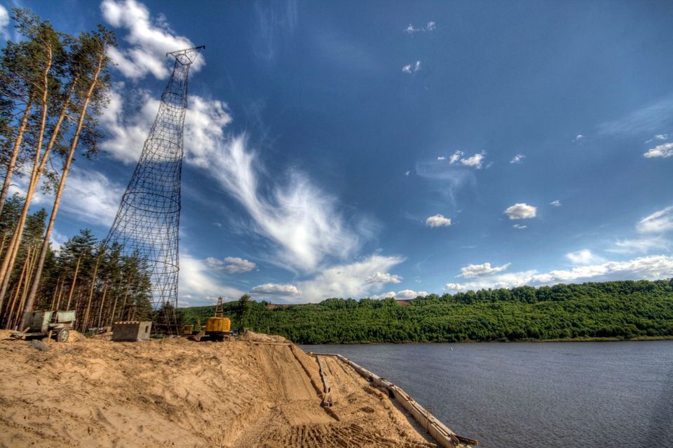 Tower beside a sand bank and the river with a yellow excavator