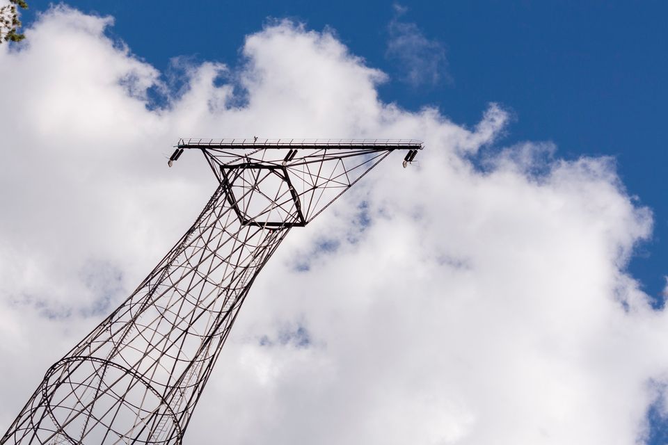 Tower top and crossarm against a cloudy blue sky