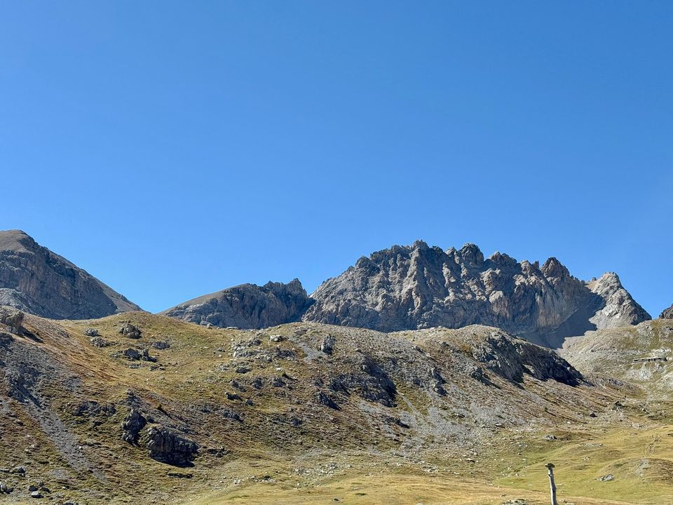 Jagged limestone crest above a wide alpine pasture