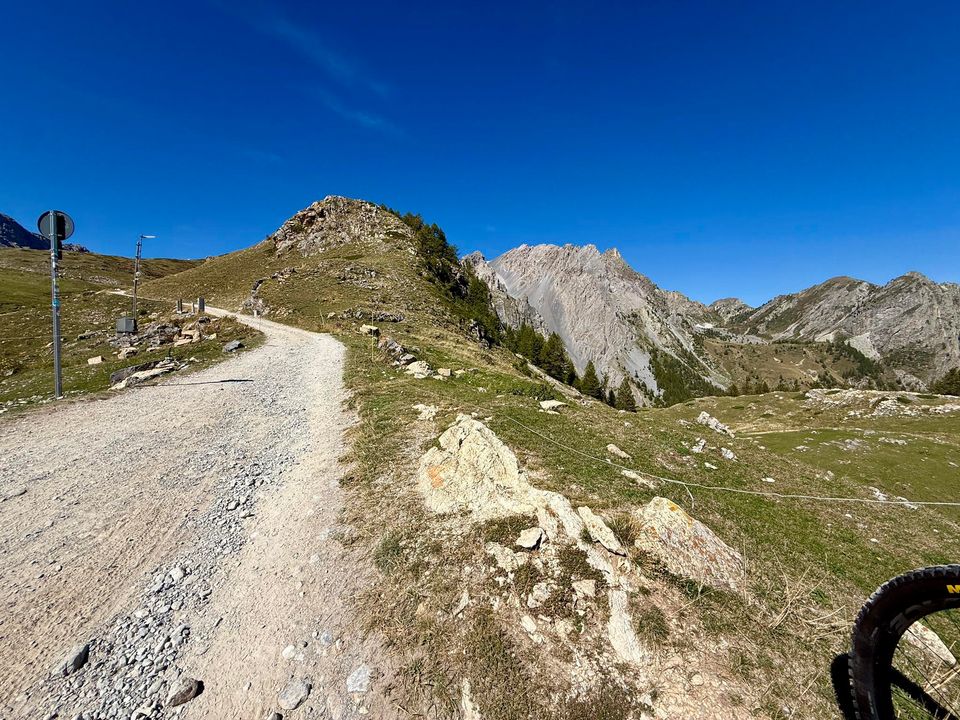 Gravel road along a ridge with rocky outcrops and distant peaks