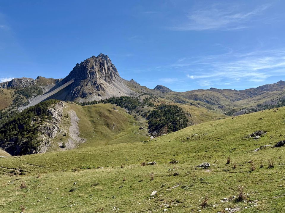 Pointed rock peak rising above green summer pastures