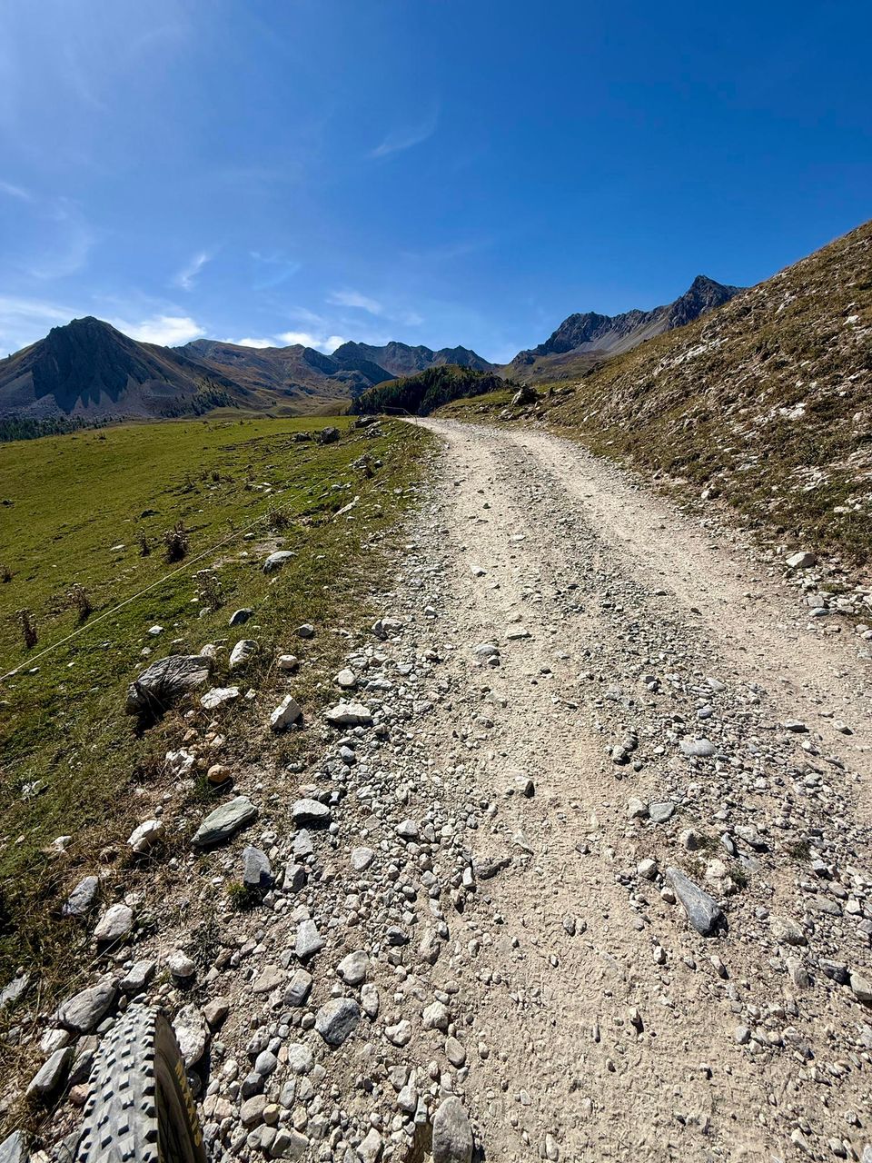 Loose stony track climbing between grassy slopes