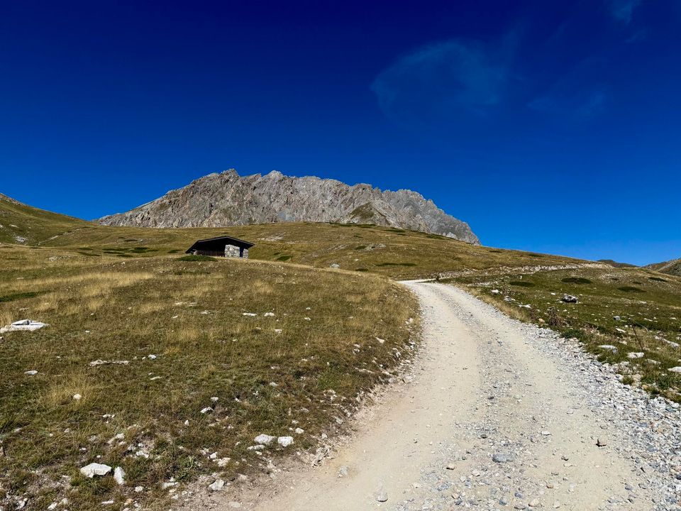 Gravel track winding across the plateau toward a small stone hut