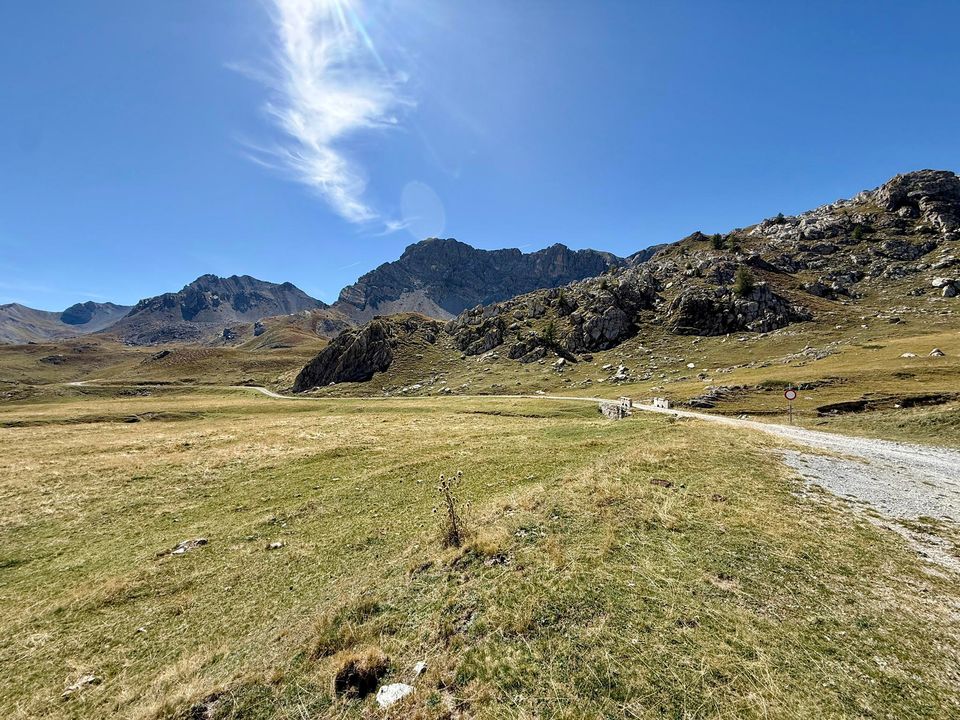 Wide grassy plateau with a gravel track and a streak of cloud