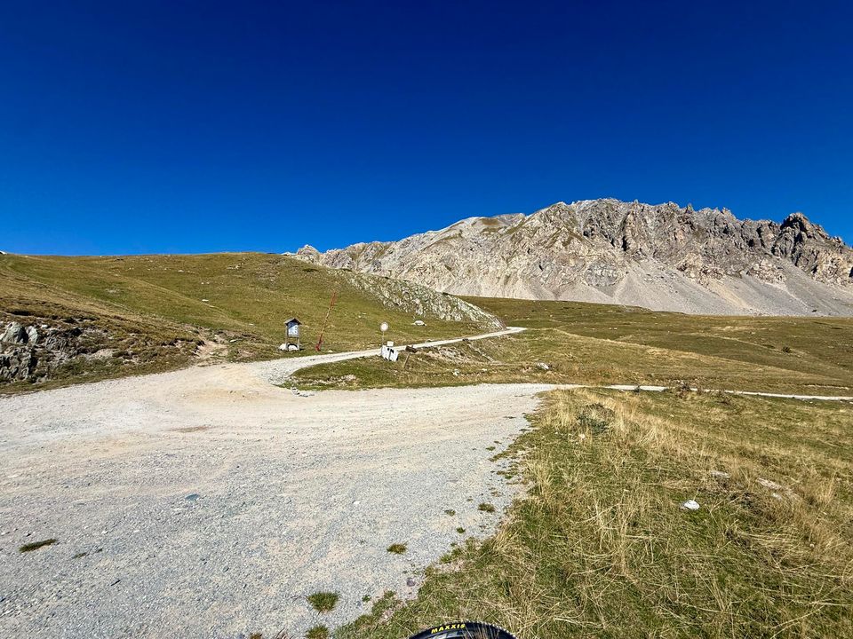 Gravel road curving across the plateau below a pale scree ridge
