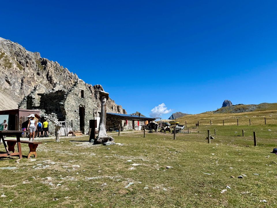 Hikers and tables outside the Gardetta refuge and its stone ruins