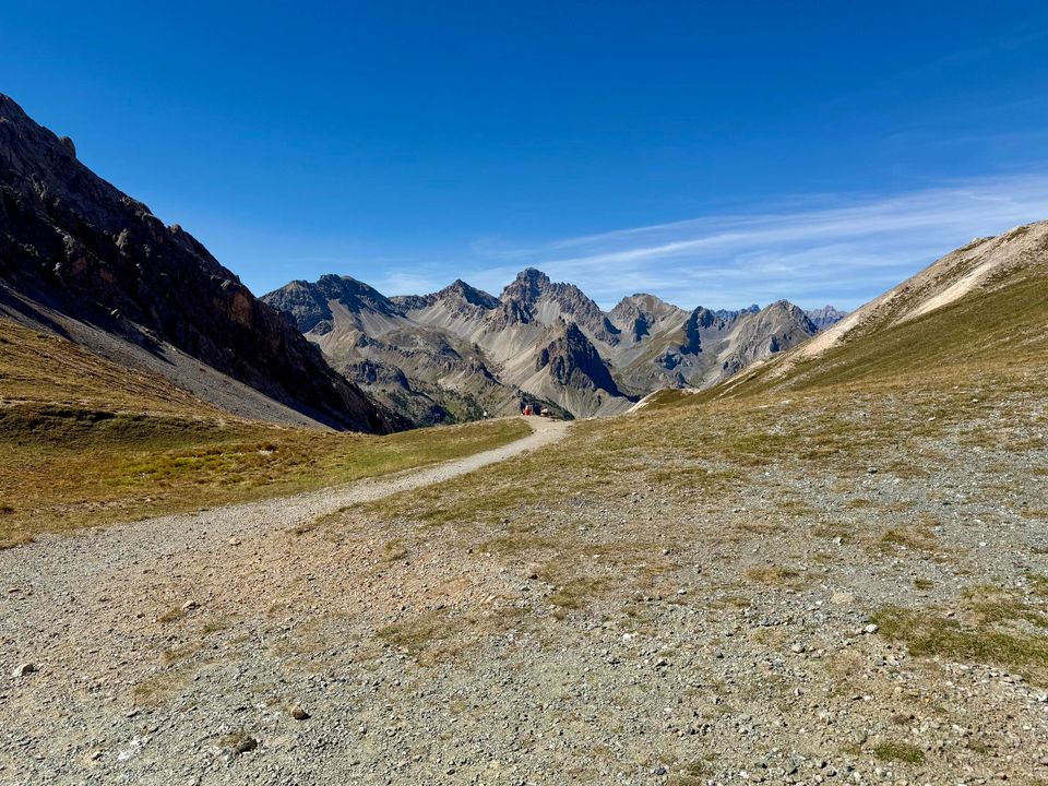 Track running down a bare valley toward a row of jagged peaks