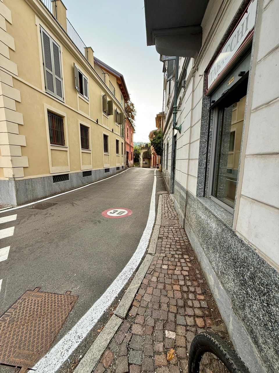 Narrow village street with a cobbled pavement and a 30 limit